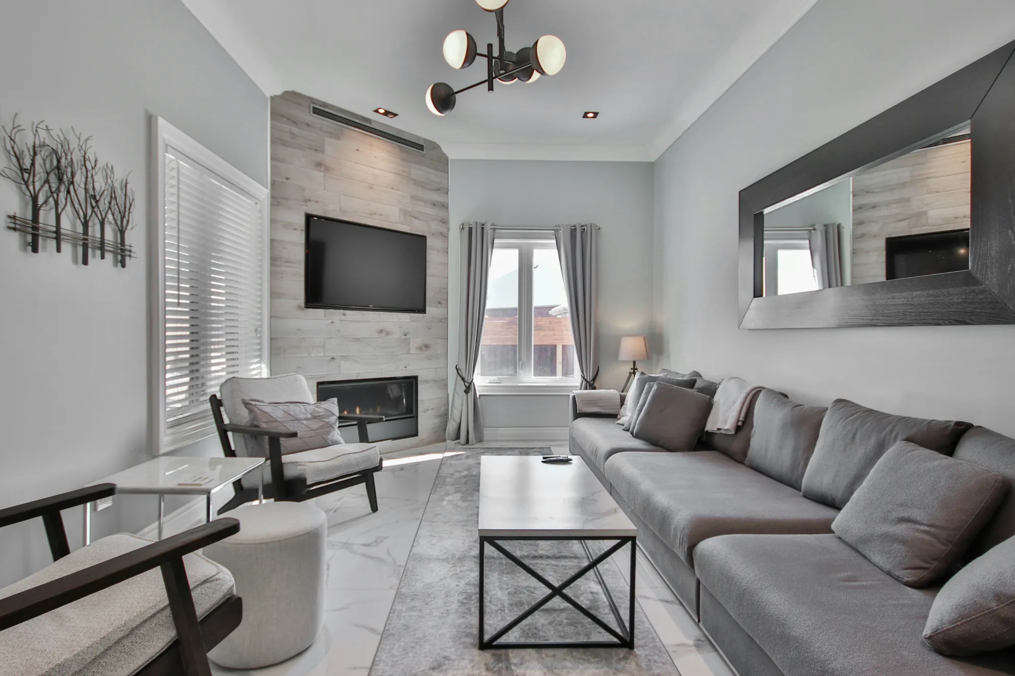 Grey living room with a long sofa, fireplace and large wall mirror