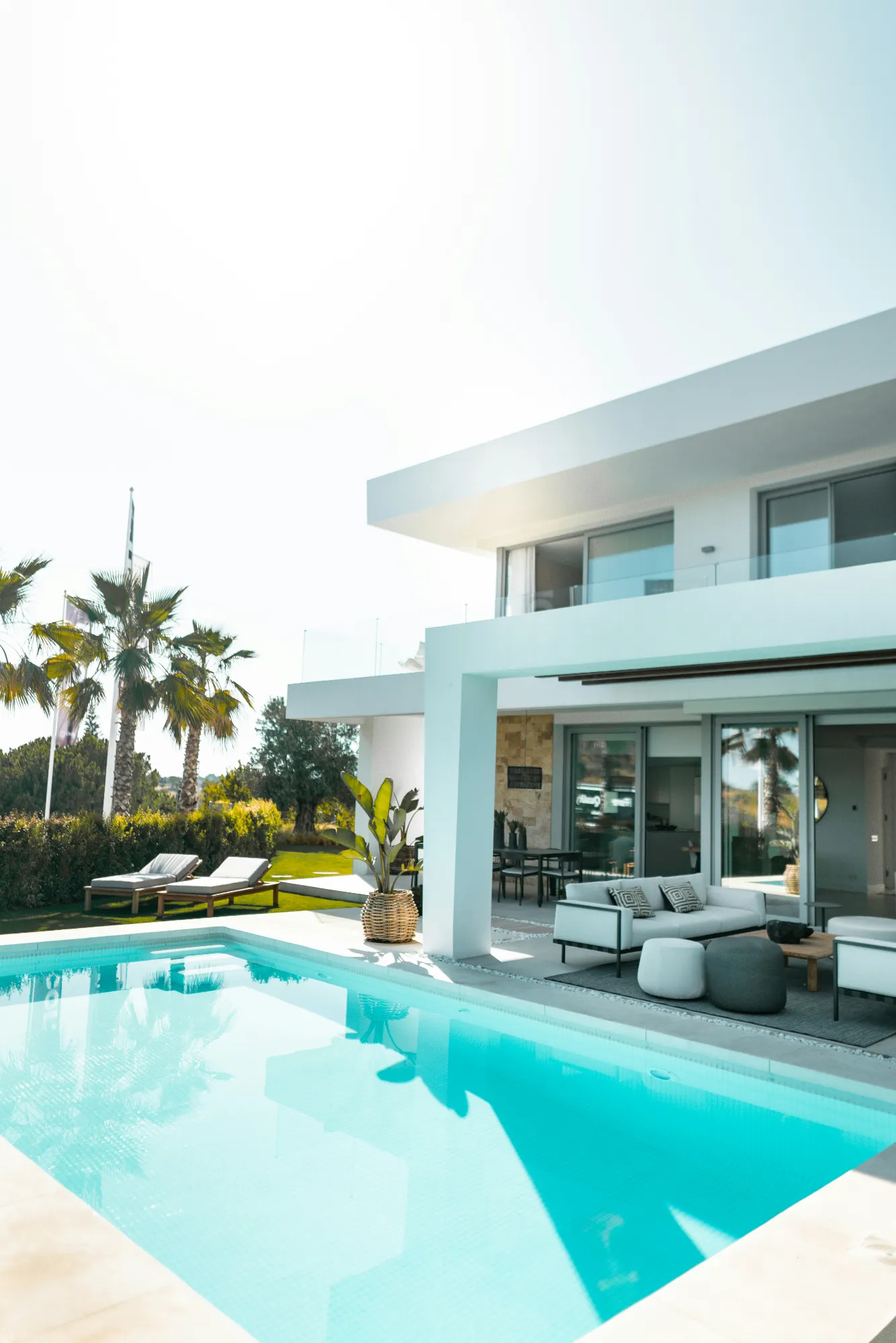Modern white home with a covered patio beside a swimming pool